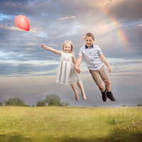 Two children flying holding a balloon, Suffolk whimsical and creative child and family photographer.